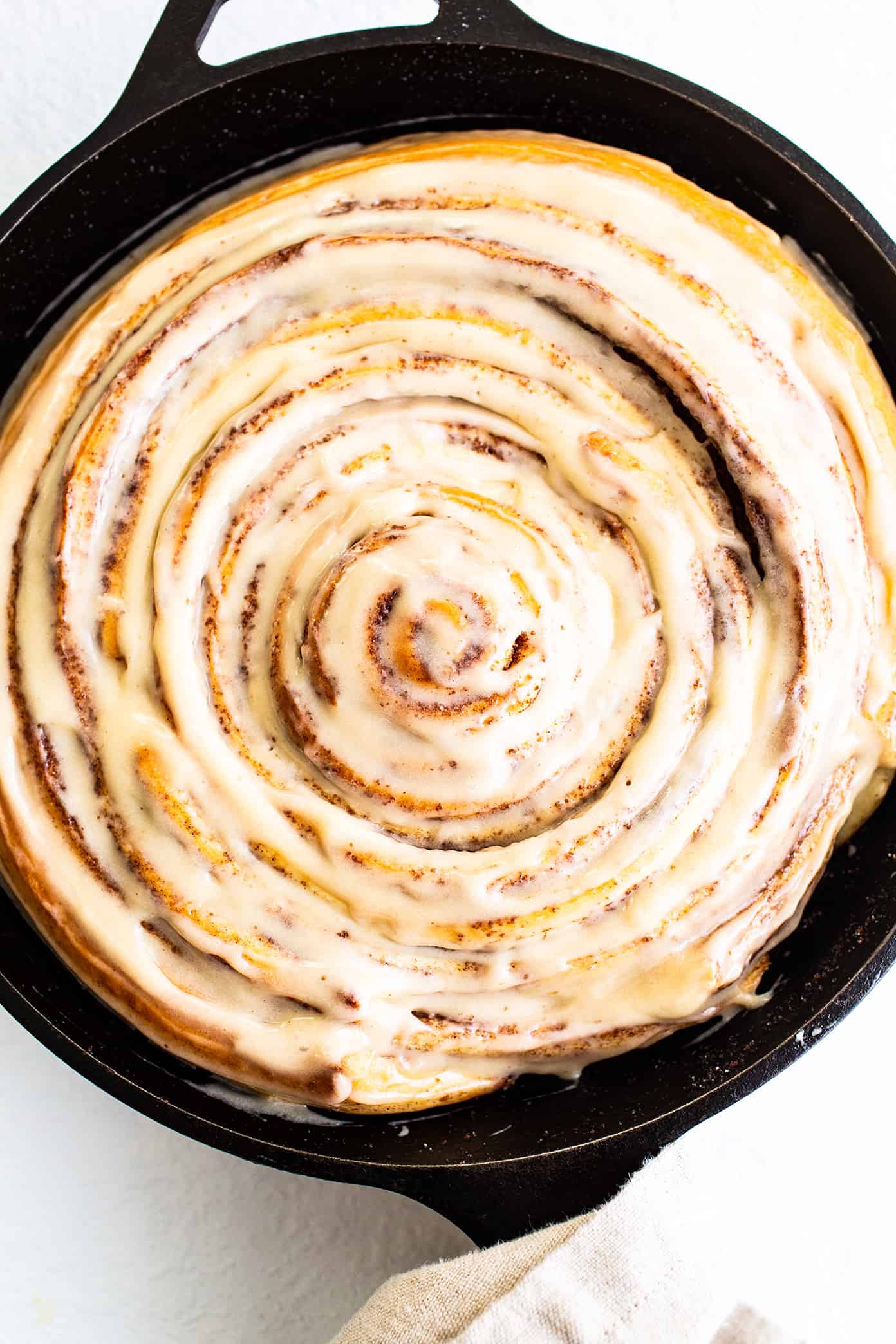 This giant cinnamon roll recipe is made with the most delicious soft dough, cinnamon-sugar filling, and a tangy cream cheese icing. Ready to go for breakfast or brunch in one hour from start to finish! | gimmesomeoven.com Giant Cinnamon Roll in Skillet with Cream Cheese Icing
