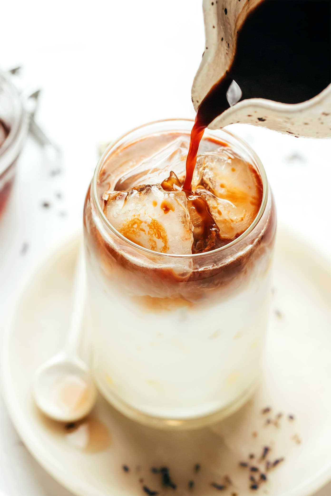 This homemade lavender latte recipe can be made hot or iced and is easy to customize with your favorite milk, espresso and add-ins. So delicious and less expensive than the coffee shop version! | gimmesomeoven.com Making an iced lavender latte with oat milk