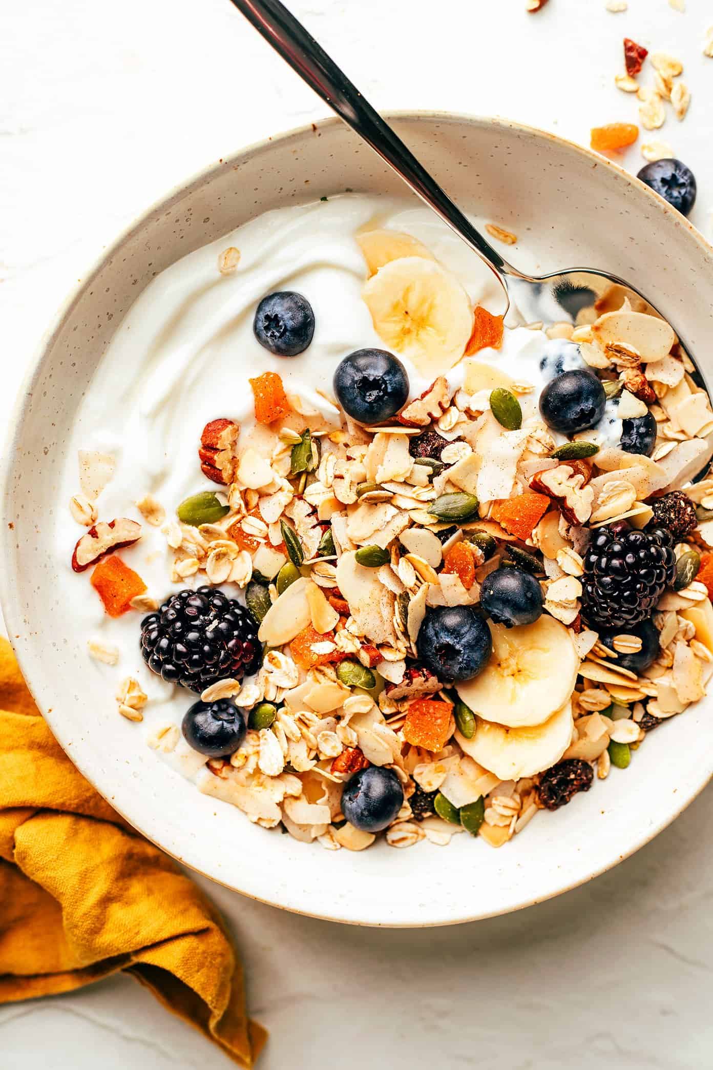This delicious homemade muesli recipe is easy to make and customize with your favorite blend of oats, nuts, seeds, dried fruit, coconut (optional) and spices. Serve with hot or cold milk, prep "overnight oats"-style, layer as a parfait with Greek yogurt, or however you love best. Always such a great healthy and easy breakfast! | gimmesomeoven.com Muesli with Greek yogurt, berries and bananas