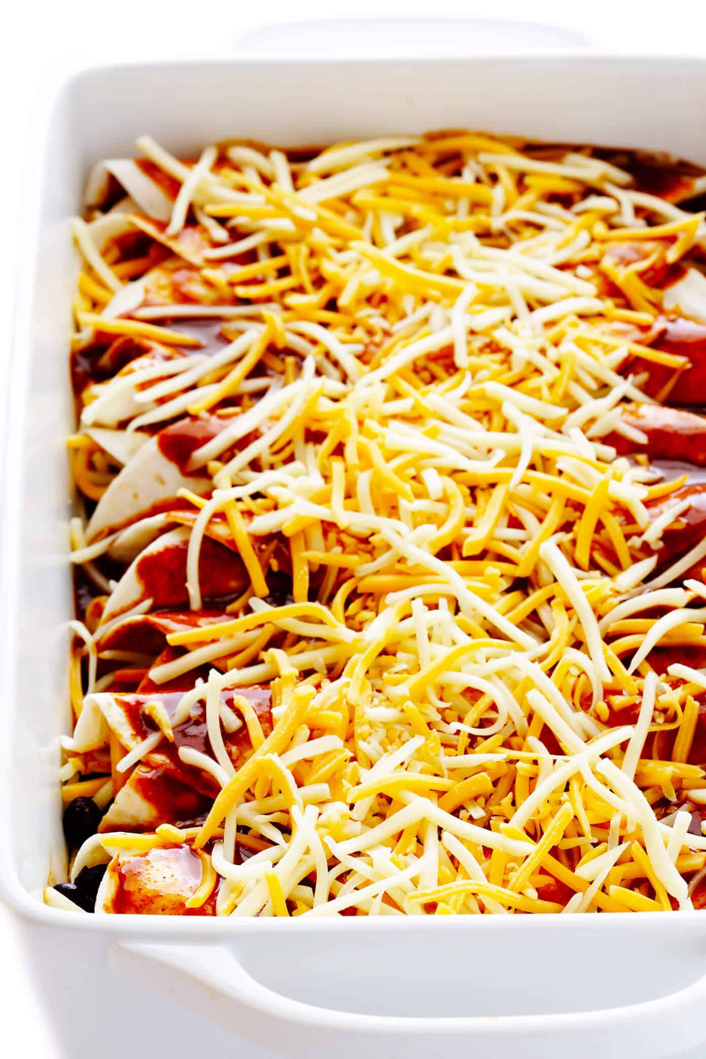 LOVE this easy chicken enchilada recipe! It's made with a delicious homemade enchilada sauce, chicken, cheese, green chiles, beans and whatever other fillings you love most. Always a great recipe when you're craving Mexican (or Tex-Mex) food for dinner -- plus these enchiladas are a great freezer meal for meal prep too. | gimmesomeoven.com Homemade Enchiladas Unbaked In Pan
